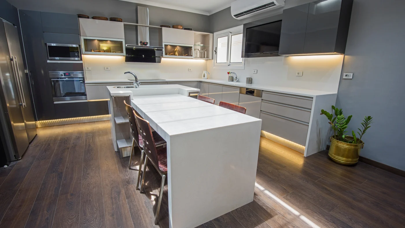 A modern kitchen with under-cabinet lighting, white cabinets, a kitchen island, and a ductless mini-split