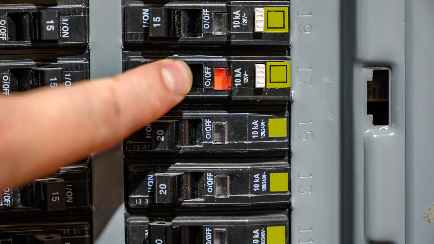 A person resets a tripped circuit breaker
