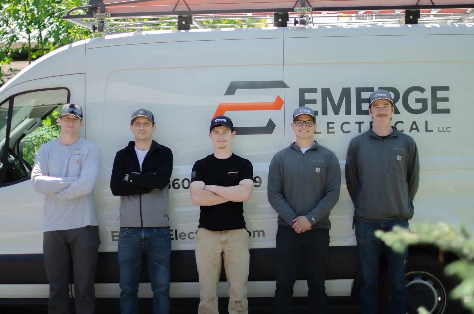 Emerge Electrical crew members standing in front of company van