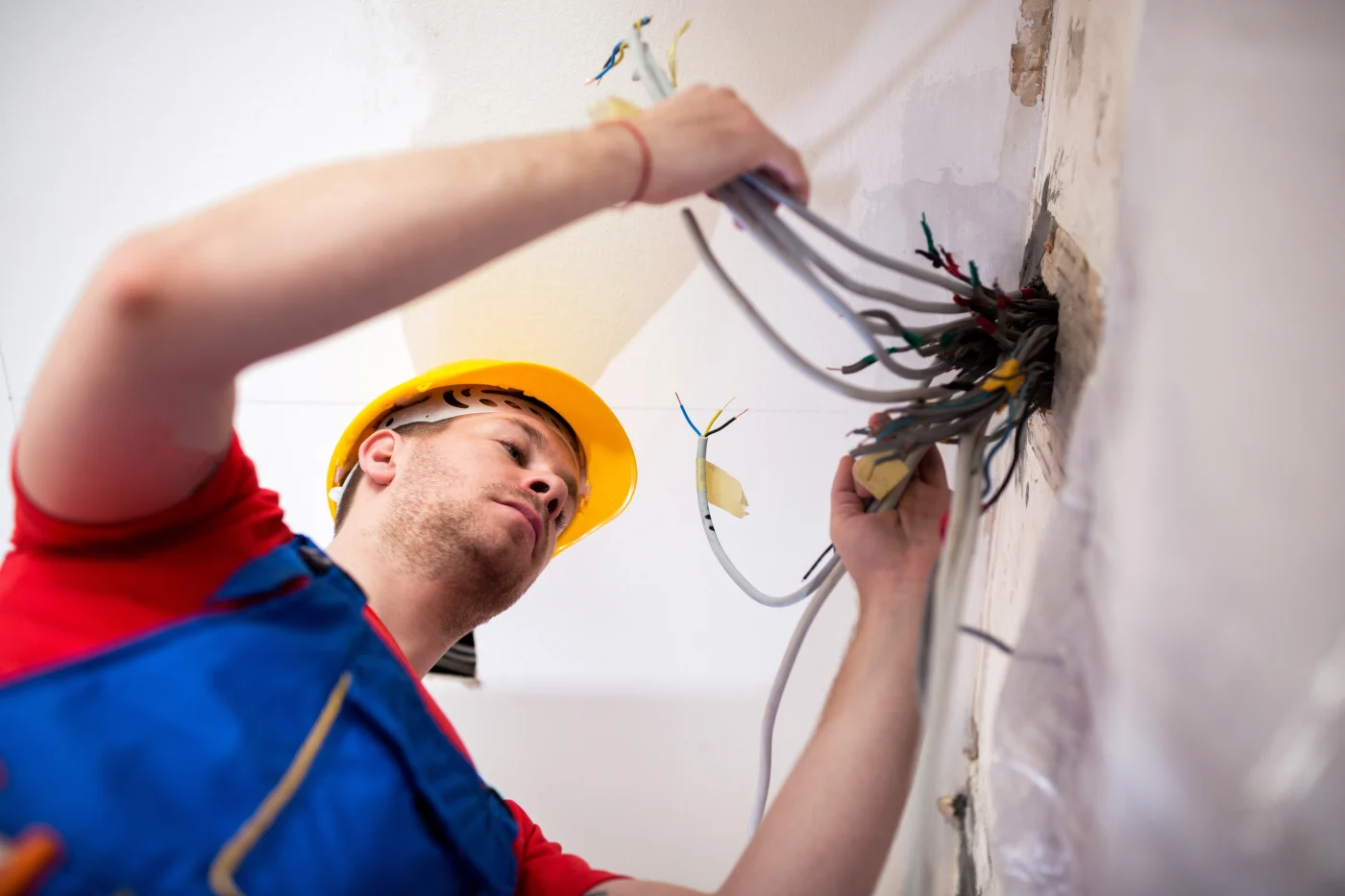 Technician pulling wires out of wall to rewire