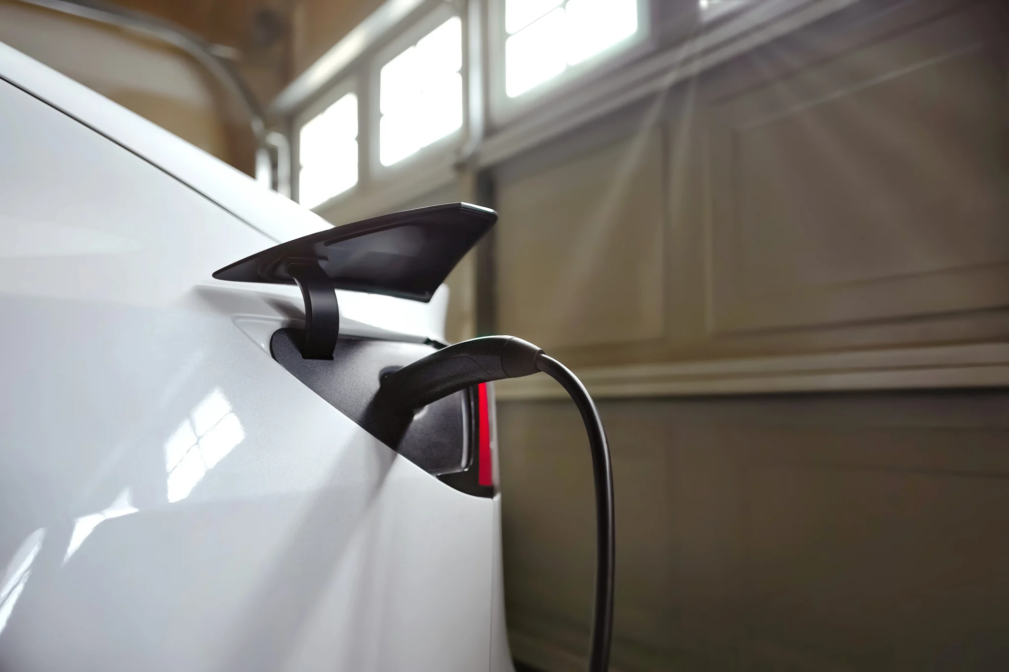 Back of a white electric car being charged in a garage