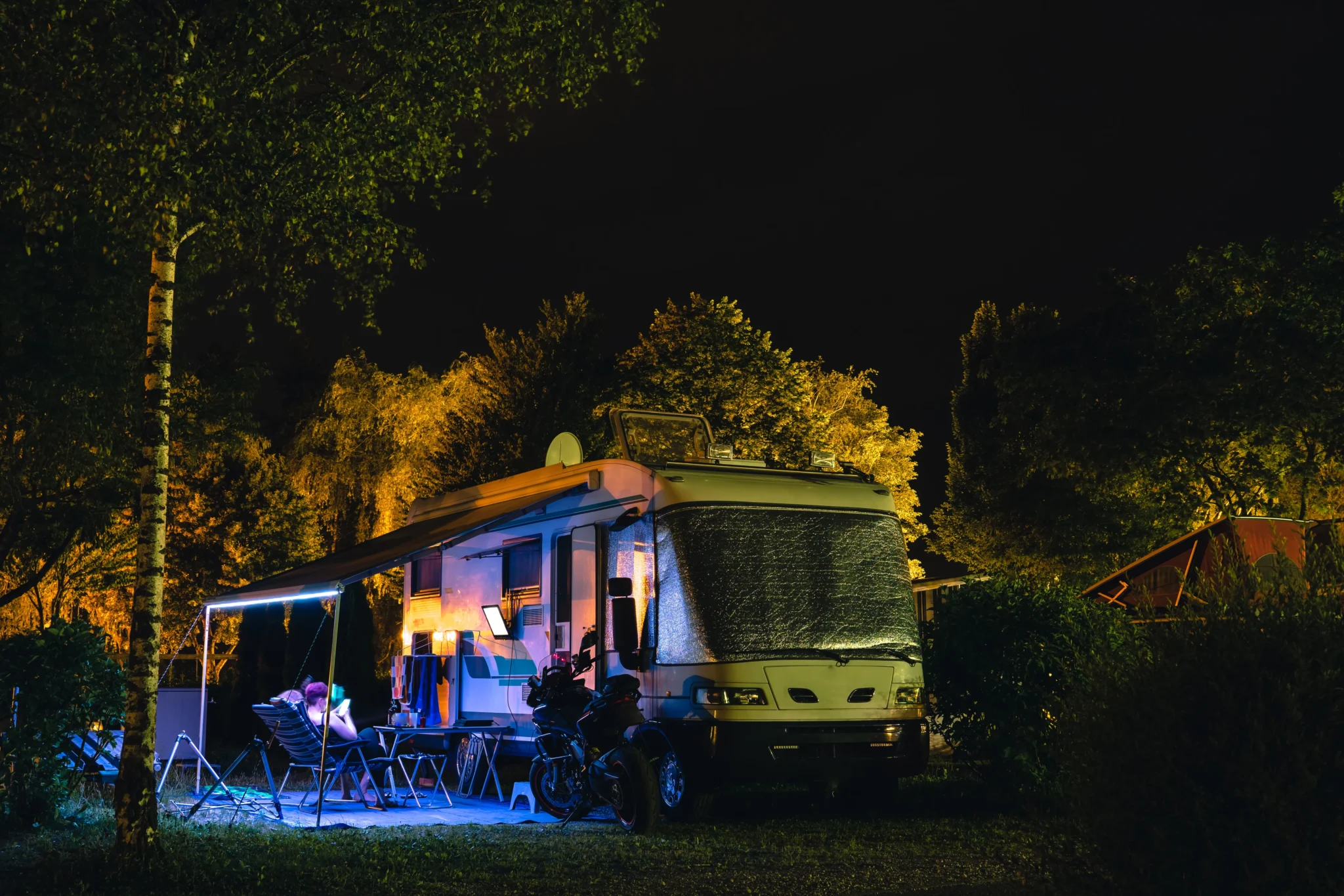 People outside RV at night watching television