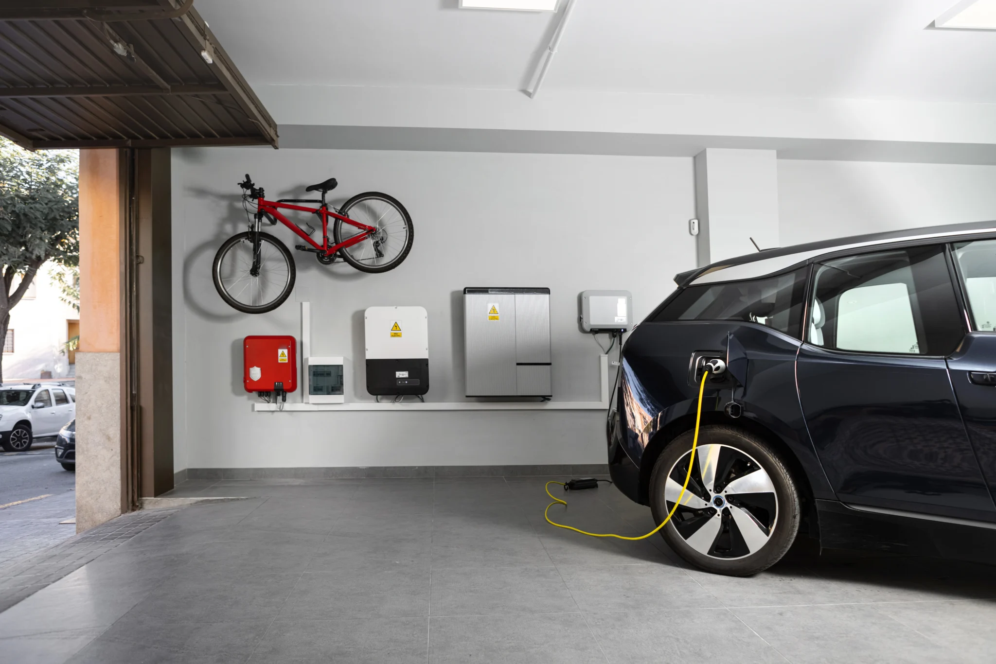 Back of a black electric car being charged in a garage