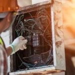 Professional electrician investigating a damaged electrical panel