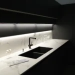 Modern kitchen with black cabinets, white marble countertops and under cabinet lights in In Turnwater, WA | Emerge Electrical