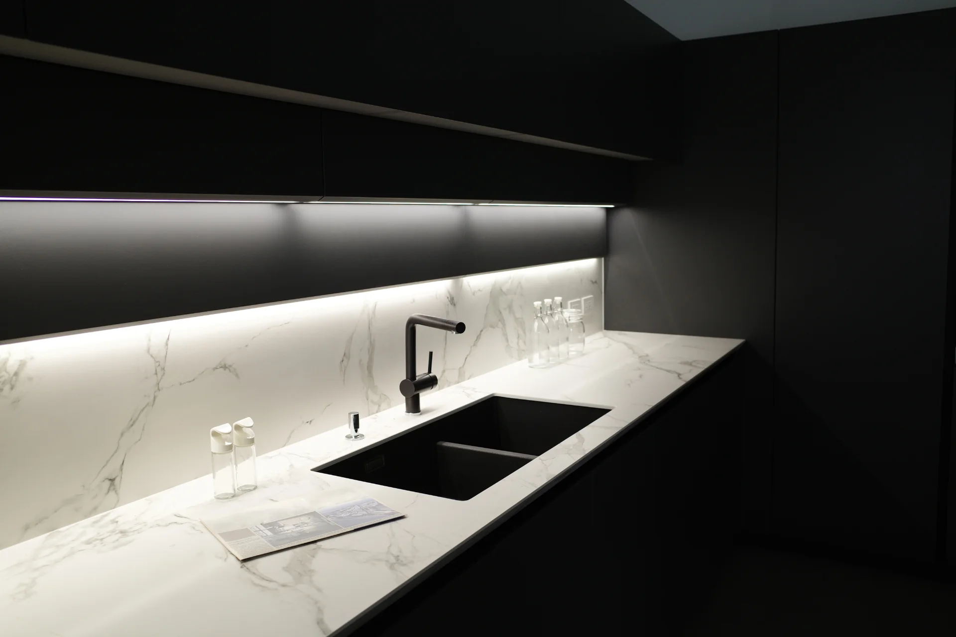 Modern kitchen with black cabinets, white marble countertops and under cabinet lights in In Turnwater, WA | Emerge Electrical